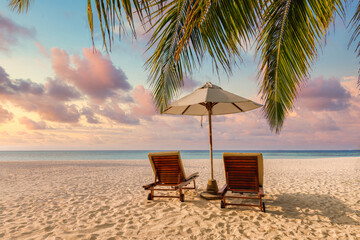 Beautiful tropical sunset shore, couple sun beds or chairs, umbrella under palm leaves. Sea sand...