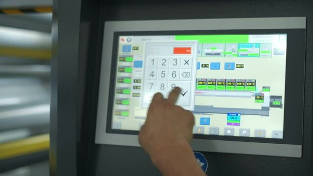 Closeup of operator taps on monitor of production machine, slow motion