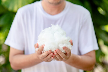 Man in white shirt holding polyester staple fiber with blur green grass background