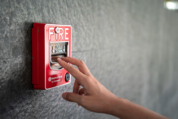 Activate fire alarm trigger system which is installed on granite wall of the building. Human action scene photo, selective focus. - obrazy, fototapety, plakaty