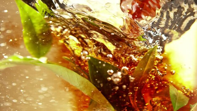 Super Slow Motion Shot of Pouring Tea into Whirl with Green Leaves at 1000fps.