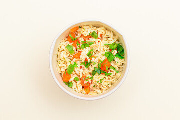 Prepared Instant Noodles with Carrot and Greens on White Background - Top View. Quick Lunch or Unhealthy Fast Food