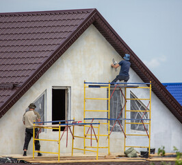 Workers are plastering the walls of the house.