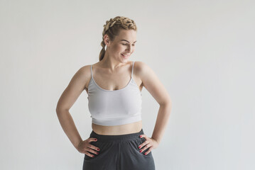 Young woman with overweight poses against a gray background in a crop top and yoga pants. Daily...