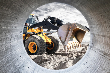 Bulldozer or loader moves the earth at the construction site against the sunset sky. Contrasting image of a modern loader or bulldozer. Construction heavy equipment for earthworks.