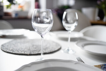 Empty glasses set in living room. Romantic table setting with white tablecloth, plates, crystal glasses. High quality photo