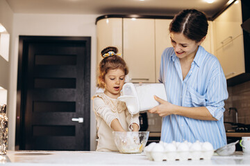 Mother with daughter preparing dough at the kitchen