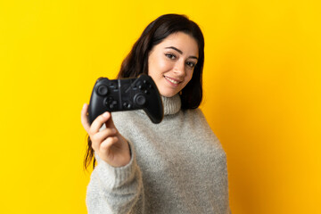 Woman playing with a video game controllerisolrted on yellow background with happy expression