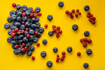 Close-up of blueberries and red currant on a bright yellow background 