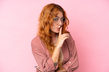 Young caucasian woman isolated on pink background With glasses and doing silence gesture