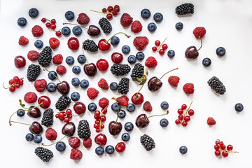 Summer berries scattered in random order on a white background, flatlay top view