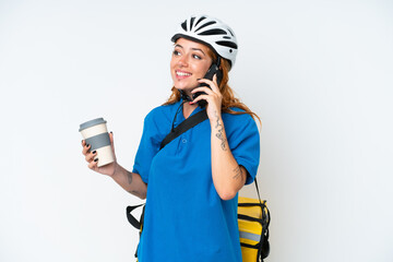 Young caucasian woman with thermal backpack isolated on white background holding coffee to take away and a mobile