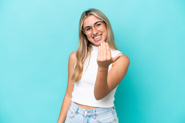 Young caucasian woman isolated on blue background inviting to come with hand. Happy that you came