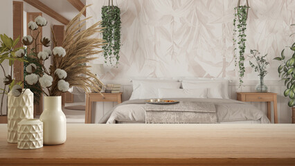 Wooden table, desk or shelf close up with ceramic vases with cotton flowers over bohemian bedroom with rattan furniture, boho style interior design concept