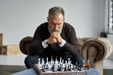Senior thoughtful man playing chess with himself