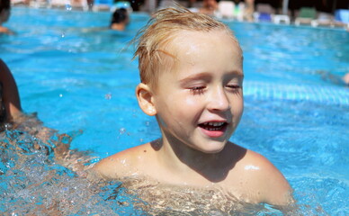 A boy is cheerful playing in the pool at the water park in the summer on a sunny day selective...