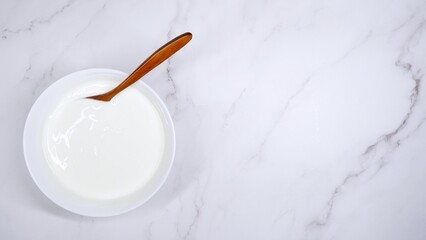 Top view of pure fermented natural yoghurt on a light marble plate
