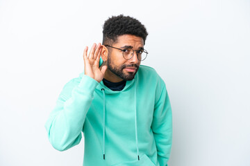 Young Brazilian man isolated on white background listening to something by putting hand on the ear