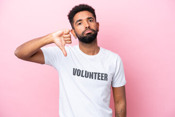 Young volunteer man isolated on pink background showing thumb down with negative expression