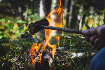 man preparing a sausage over a fire in the middle of the forest