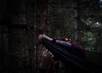 Fototapeta na wymiar a man hanging up his hammock to take a break from hiking in the middle of a mountain forest