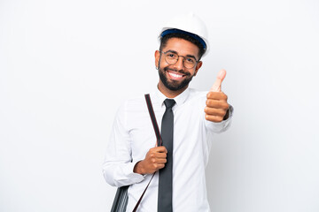Young architect Brazilian man with helmet and holding blueprints isolated on white background with thumbs up because something good has happened