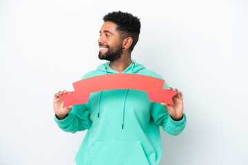 Young Brazilian man isolated on white background holding an empty placard and looking side