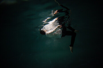 Beautiful underwater shooting, guy in white shirt and pants has fallen under the water and...