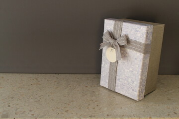 Gray-blue gift box on a dark gray background, decorated with a bow, creating a romantic atmosphere....