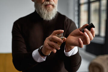 Senior man applying aromatic perfume on his wrist