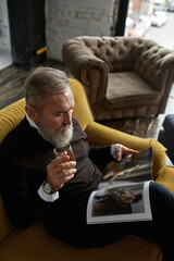 Top of senior man drink brandy and read journal