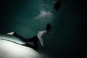 Beautiful underwater shooting, guy in white shirt and pants has fallen under the water and is...