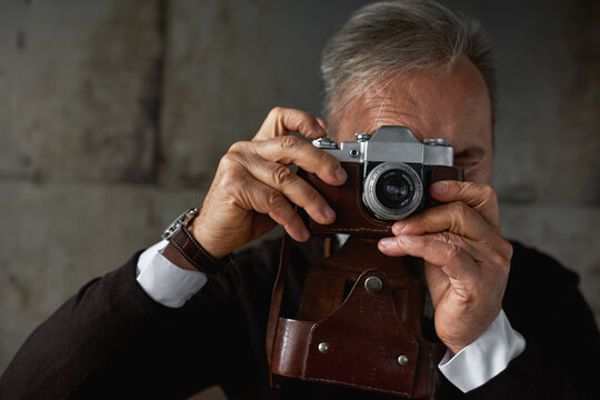 Senior caucasian man taking photo on old camera