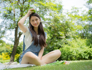 Naklejka na ściany i meble Young girl person holding apple fruit, fresh vitamin diet, healthy lifestyle, portrait. Joyful beautiful Asian teenage happy sitting outdoor leisure activity in green park. Smiling child play apple