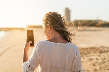 Chica joven en zona de playa junto a tienda de surf  al atardecer en la arena