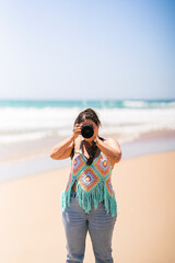 Chica joven guapa feliz con su camara fotografica tomando fotos en la playa