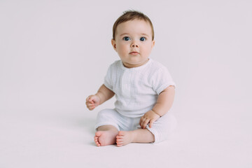 Small baby boy in a white bodysuit crawling on a white background