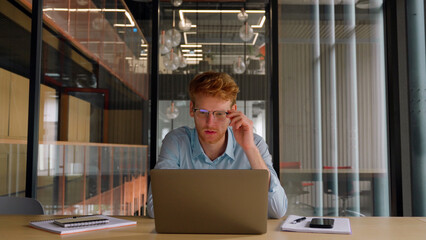 Young worried businessman checks financial crisis report on laptop computer. 