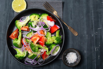 Healthy food vegetable broccoli salad in bowl on black wood background.