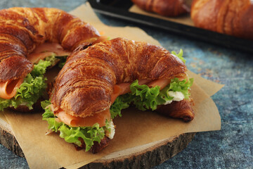 Freshly baked croissants with salmon and salad on the table