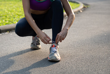 Young sports woman tying shoe lace in the park before running.