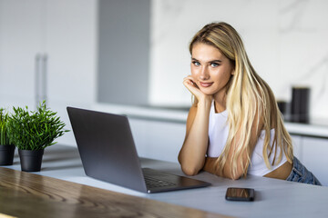 Fototapeta premium Happy young woman using laptop in cook room
