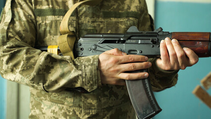 a soldier in camouflage uniform takes aim with his machine gun, preparing to fire close-up. fighting inside the building. firing at the enemy army. Kalashnikov shooting. combat clashes