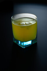 glass of lemonade with ice yellow with black background