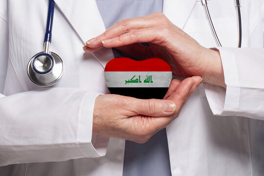 Iraqi Doctor Holding Heart With Flag Of Iraq Background. Healthcare, Charity, Insurance And Medicine Concept