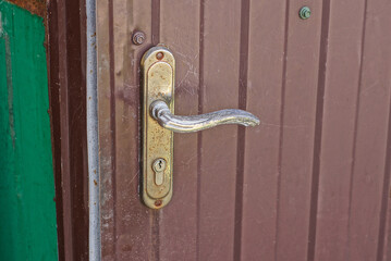 one gray iron doorknob on a brown metal door in the street