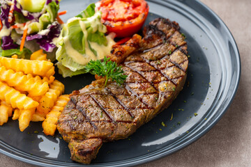 Grilled Sirloin Beef Steak with french fries and salads. Serve on Black Plate. Negative Space.