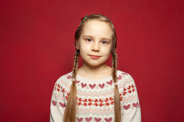 Little cute child kid girl 6-7 years old wearing sweater isolated against red wall background, children studio portrait