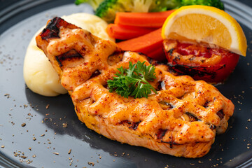 Grilled salmon fillets with mentai sauce and mash potato plating on black plate with negative space for text.