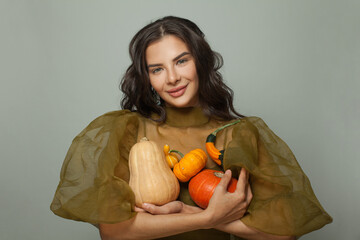 Cheerful young woman holding different orange pumpkins on white background. Thanksgiving or...
